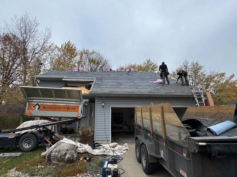 Hershberger Brothers Roofing crew working on a roof, with the trailer in the driveway