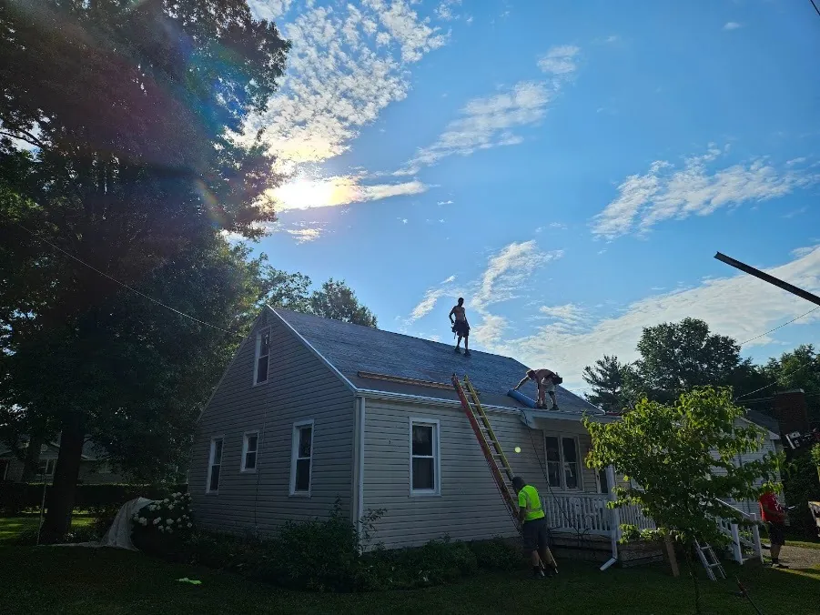 Hershberger Brothers Roofing crew working on the roof of a small home, with a ladder against the porch