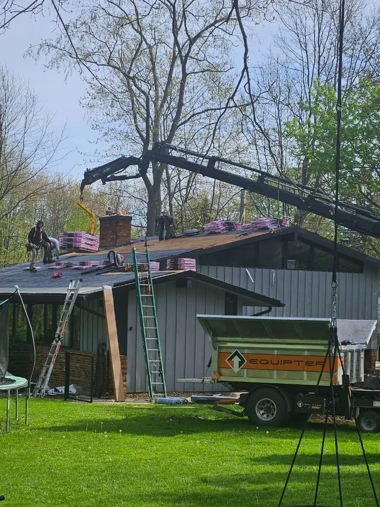Bundles of new shingles lifted onto the roof during a roof installation