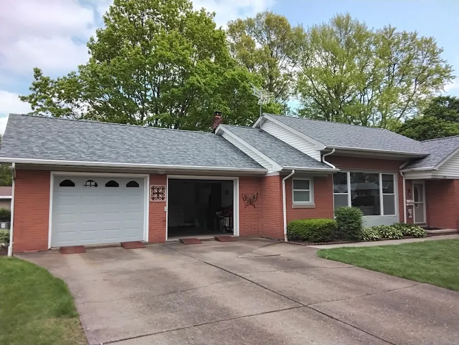 Brick ranch home with white gutters and downspouts along a new shingle roof
